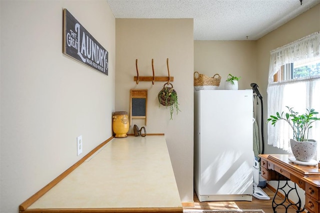 interior space with a textured ceiling, wood finished floors, and baseboards