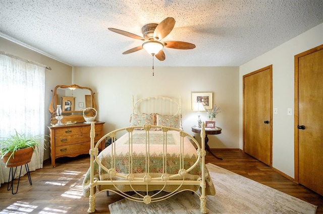 bedroom with ceiling fan, a textured ceiling, two closets, and wood finished floors