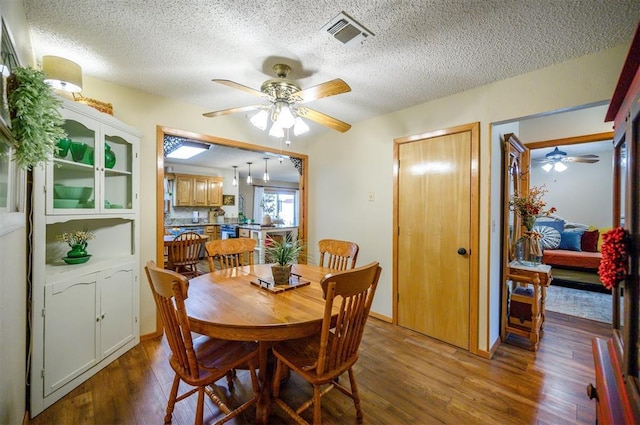 dining area with ceiling fan, a textured ceiling, visible vents, and wood finished floors