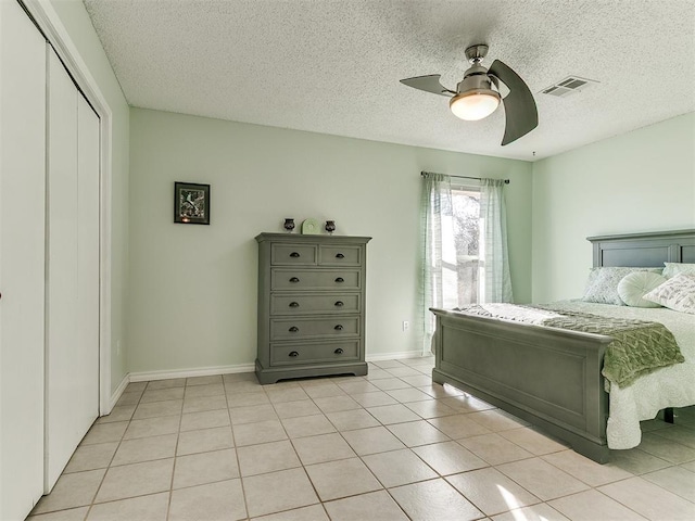 bedroom featuring light tile patterned floors, ceiling fan, visible vents, baseboards, and a closet