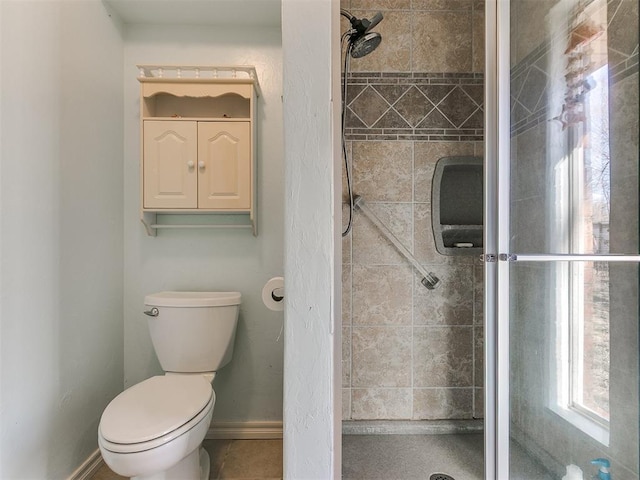 full bath featuring toilet, a shower stall, and baseboards