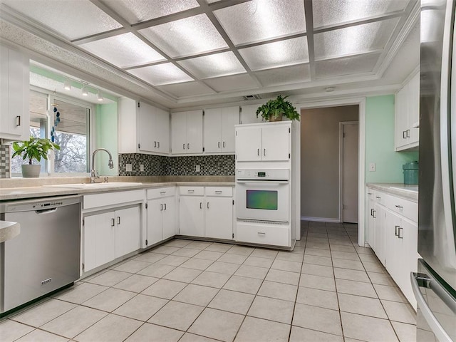 kitchen with white cabinets, stainless steel appliances, a sink, and light countertops