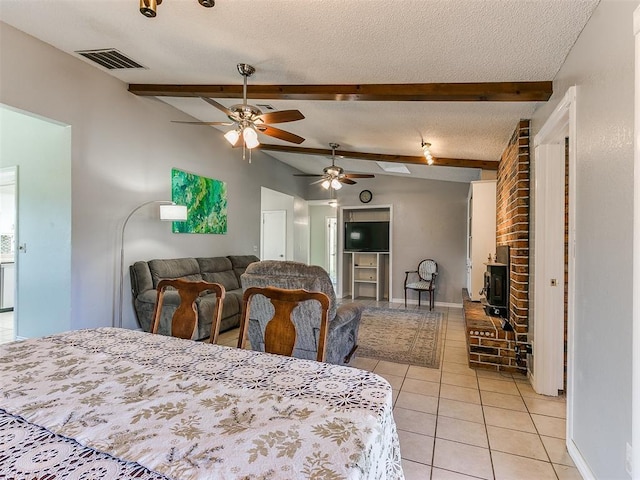 dining space with vaulted ceiling with beams, light tile patterned floors, visible vents, a brick fireplace, and a textured ceiling