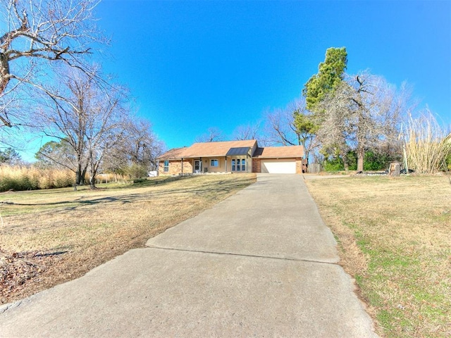 ranch-style house featuring a garage, a front yard, and concrete driveway