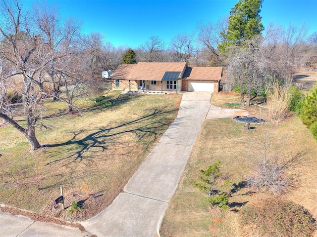 view of front facade with driveway, a porch, an attached garage, and a front yard