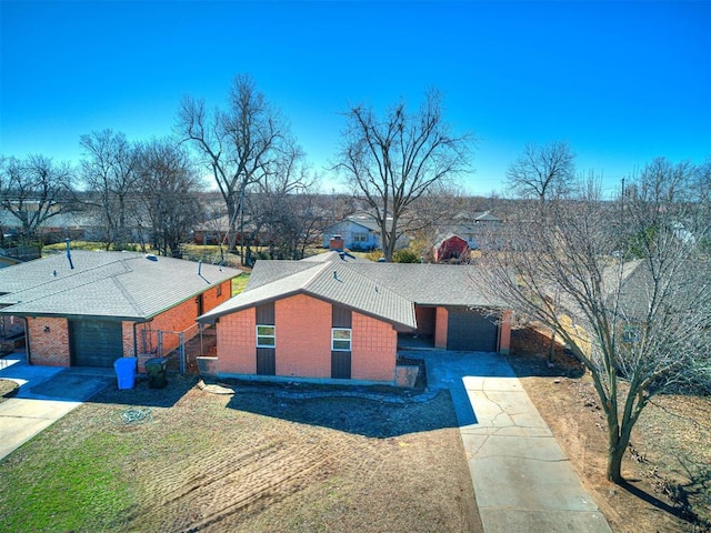 view of front facade with driveway, an attached garage, roof with shingles, and brick siding