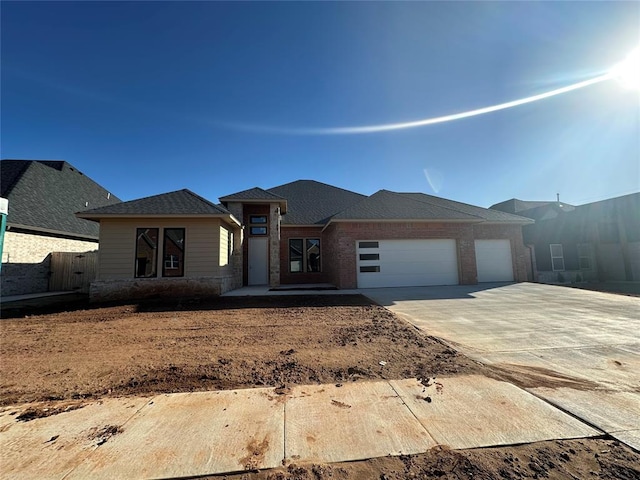 prairie-style house with a garage, concrete driveway, and brick siding