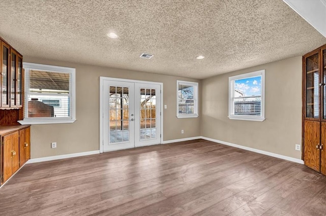 interior space with baseboards, wood finished floors, and french doors