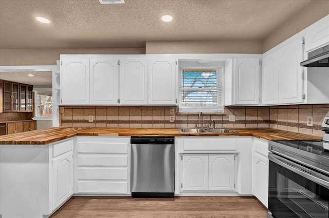 kitchen with wooden counters, appliances with stainless steel finishes, light wood-type flooring, and a sink