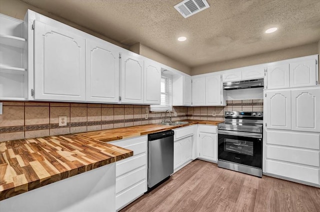 kitchen with visible vents, butcher block countertops, appliances with stainless steel finishes, under cabinet range hood, and a sink