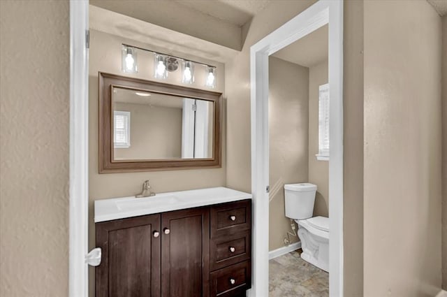 bathroom with baseboards, vanity, and toilet