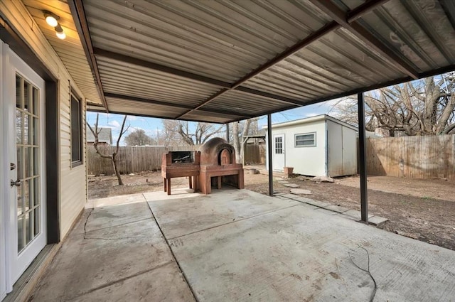 view of patio with an outbuilding, a carport, french doors, and a fenced backyard