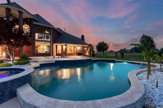 pool at dusk featuring a patio, an outdoor pool, area for grilling, and an in ground hot tub