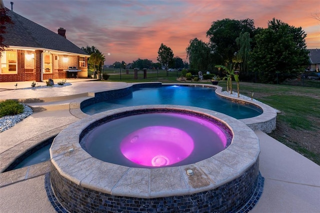 view of swimming pool featuring a grill, fence, a yard, a patio area, and a pool with connected hot tub