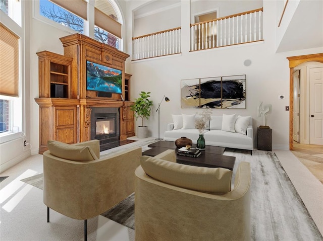 living area with a glass covered fireplace, visible vents, a towering ceiling, and baseboards