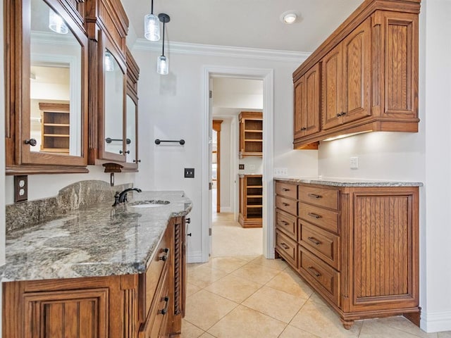 kitchen with light tile patterned floors, stone countertops, crown molding, brown cabinetry, and pendant lighting