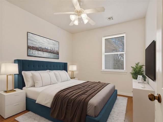 bedroom with baseboards, wood finished floors, visible vents, and a ceiling fan