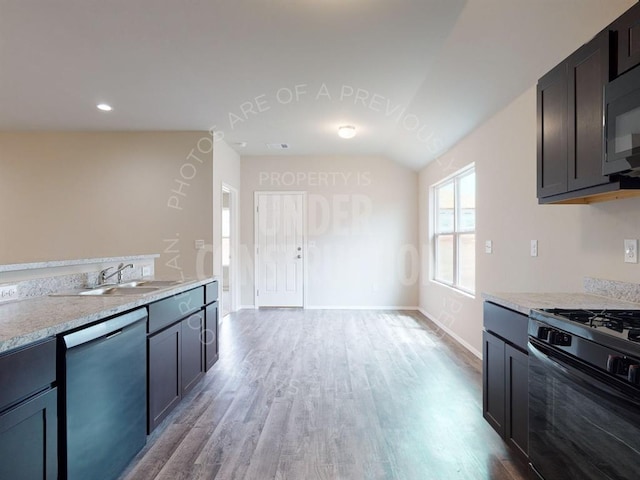 kitchen featuring lofted ceiling, a sink, baseboards, light wood-style floors, and black appliances