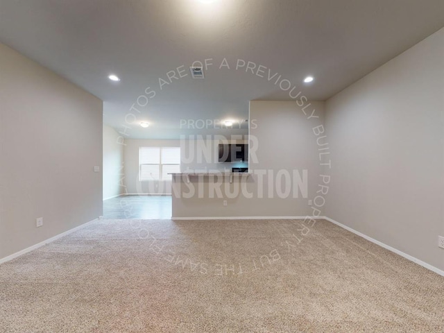 unfurnished living room with carpet floors, baseboards, and recessed lighting