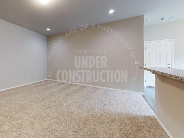 carpeted spare room featuring baseboards, visible vents, and recessed lighting