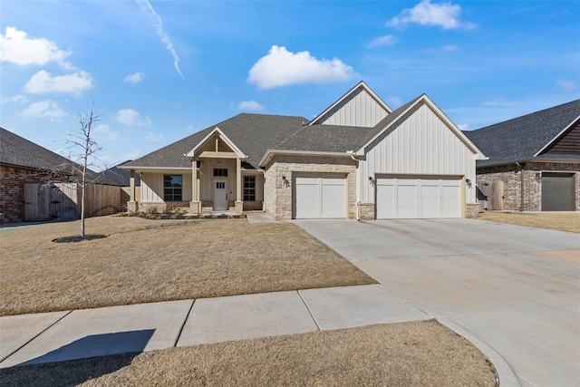 view of front facade featuring a garage, fence, driveway, stone siding, and roof with shingles