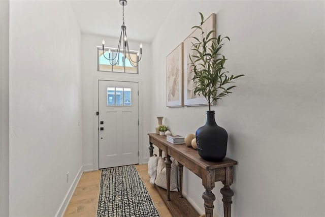 entryway featuring light wood-style floors, baseboards, and an inviting chandelier