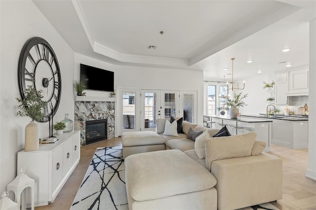 living room featuring french doors, a fireplace, recessed lighting, a raised ceiling, and visible vents