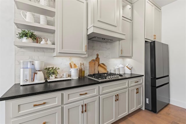 kitchen featuring open shelves, appliances with stainless steel finishes, wall chimney exhaust hood, and backsplash