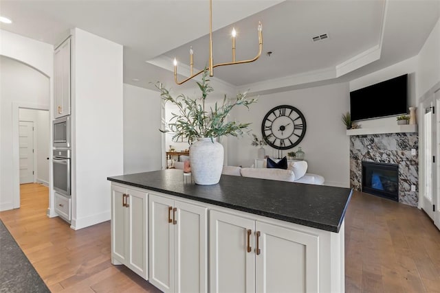 kitchen with dark countertops, a raised ceiling, visible vents, appliances with stainless steel finishes, and open floor plan