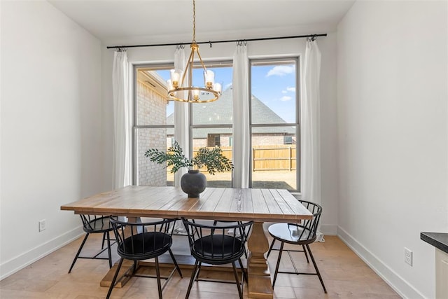 dining space featuring a chandelier and baseboards