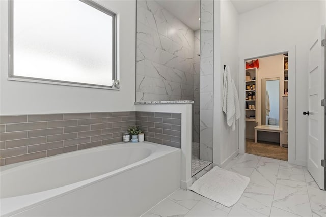 full bath with a walk in shower, marble finish floor, a garden tub, and a walk in closet