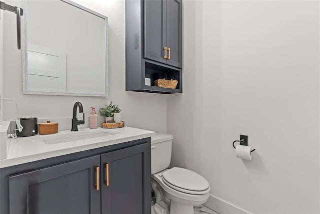 bathroom with marble finish floor, vanity, toilet, and baseboards