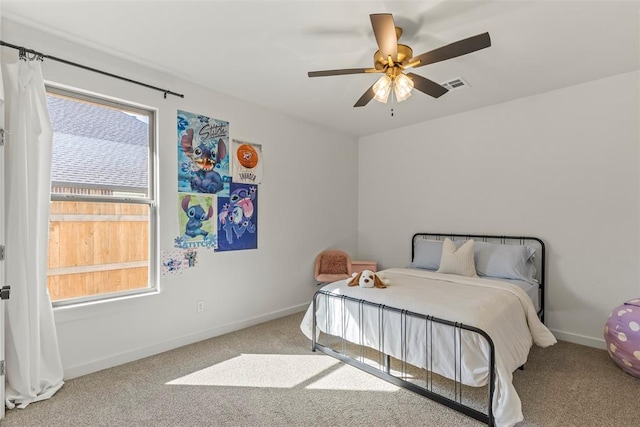 carpeted bedroom featuring a ceiling fan, multiple windows, visible vents, and baseboards