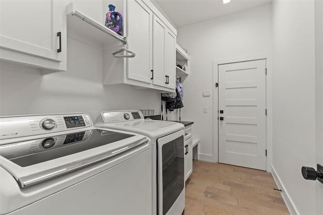 clothes washing area with light wood-type flooring, cabinet space, baseboards, and washer and clothes dryer