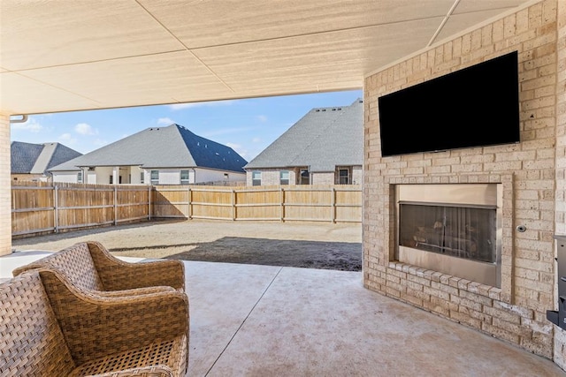 view of patio with an outdoor brick fireplace and a fenced backyard