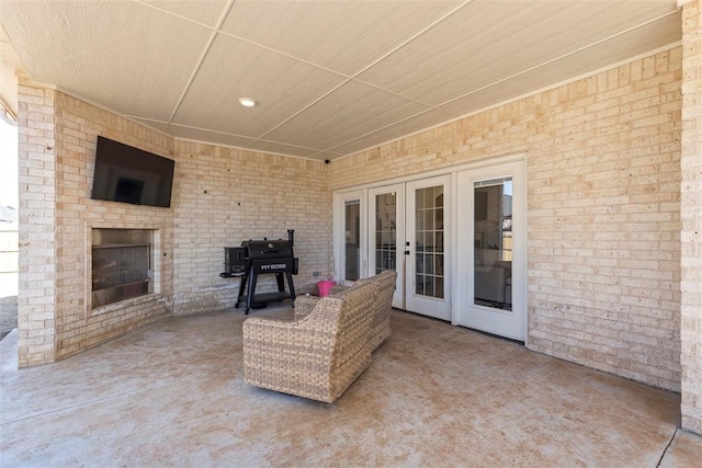 view of patio with an outdoor brick fireplace, a grill, and french doors