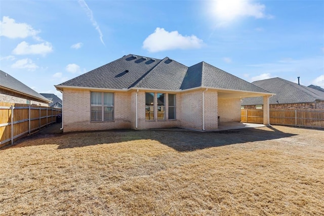 back of house with brick siding, roof with shingles, a patio area, and a fenced backyard