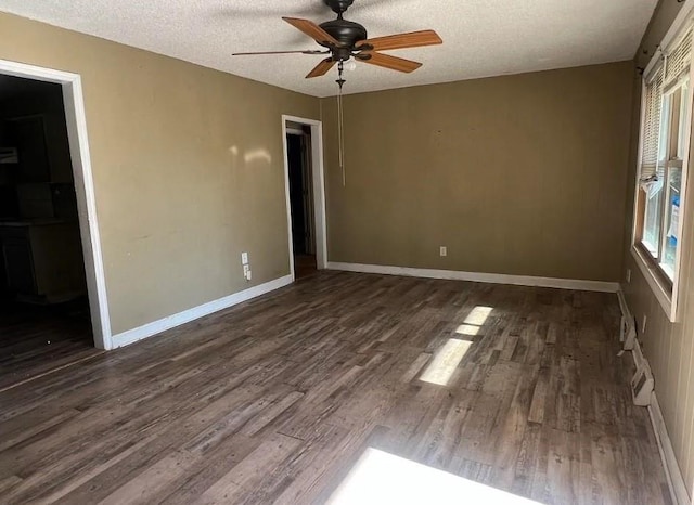 unfurnished bedroom featuring a ceiling fan, dark wood-style flooring, a textured ceiling, and baseboards