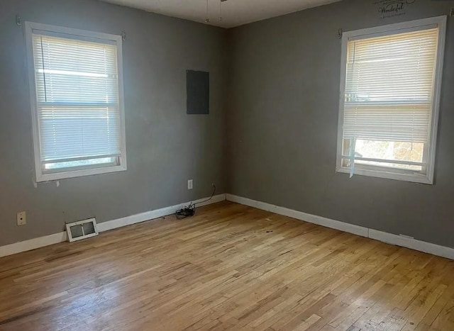 empty room with light wood-style flooring, a ceiling fan, visible vents, and baseboards