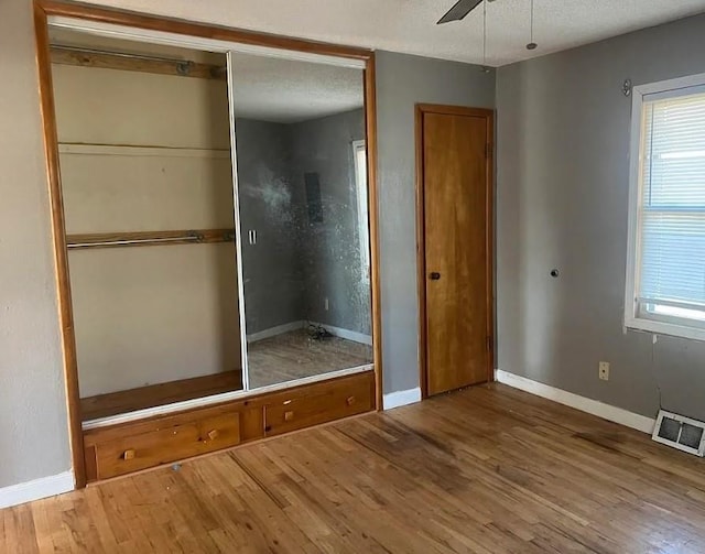 unfurnished bedroom with baseboards, a textured ceiling, visible vents, and wood finished floors