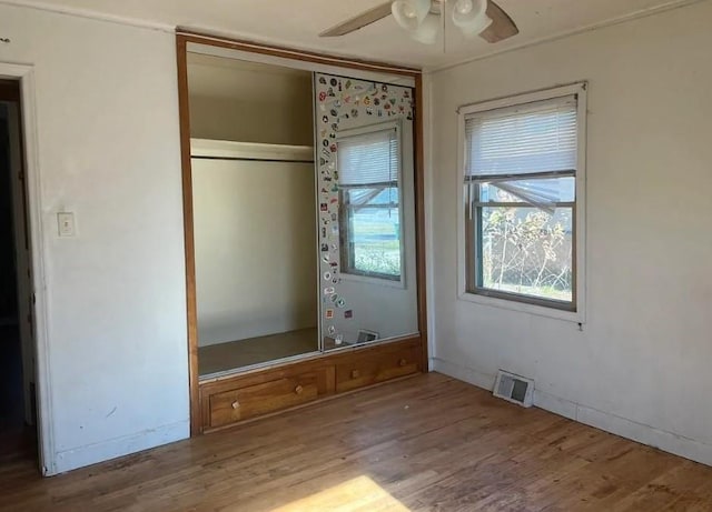 unfurnished bedroom with a ceiling fan, a closet, visible vents, and wood finished floors