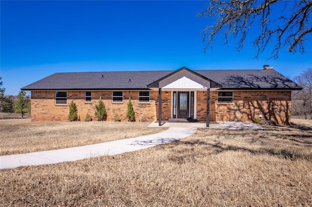 ranch-style house featuring brick siding and roof with shingles