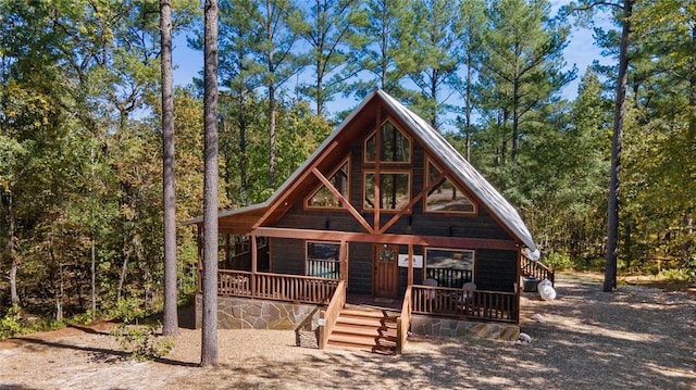 rustic home featuring a porch and a view of trees