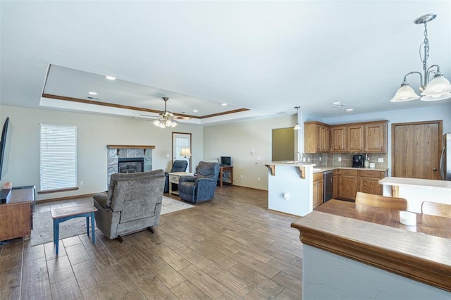 living room with a raised ceiling, light wood-style flooring, a fireplace, and a wealth of natural light