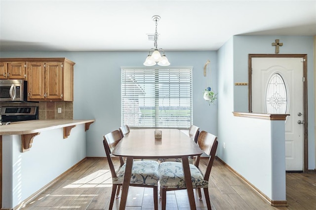 dining space with light wood finished floors, visible vents, and baseboards