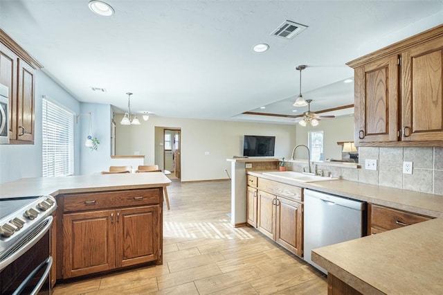 kitchen featuring a sink, dishwasher, a peninsula, and range with two ovens