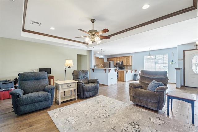 living area featuring recessed lighting, visible vents, a raised ceiling, and crown molding