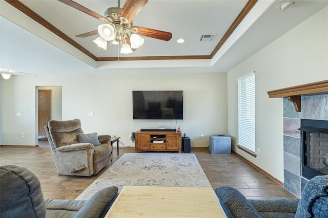 living room featuring a fireplace, a tray ceiling, and wood finished floors