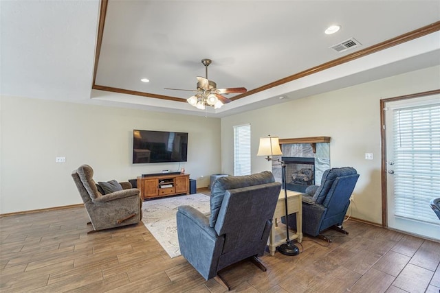 living room with visible vents, a raised ceiling, and light wood-style floors