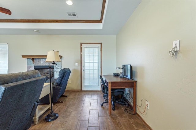 office with a tiled fireplace, wood finished floors, and visible vents